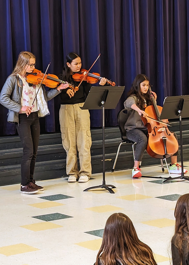 Three students play stringed instruments togehter